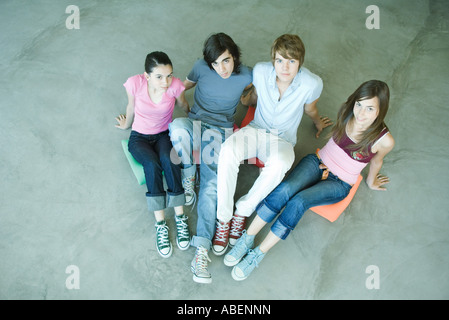 Quatre amis adolescents assis sur des coussins sur le sol, looking at camera, portrait Banque D'Images