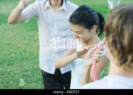 Jeunes amis jouant avec tuyau de jardin, blurred motion Banque D'Images