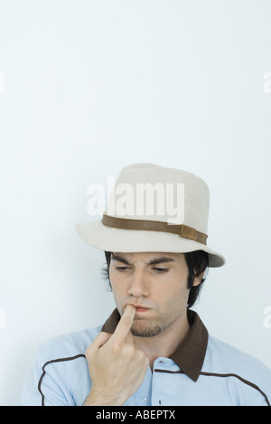 Young man biting finger, regardant vers le bas Banque D'Images