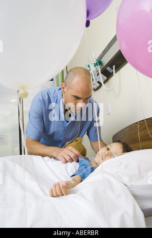 Girl lying in hospital bed, entouré par des ballons Banque D'Images