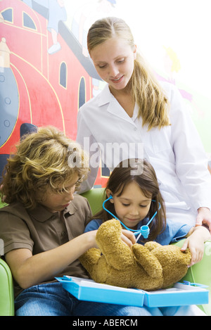 Boy and girl playing doctor avec ours Banque D'Images