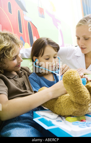 Boy and girl playing doctor avec ours Banque D'Images