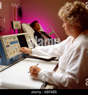 La recherche des troubles du sommeil ; un chercheur surveille les appareils d'essai, tout en observant une femme au cours de la recherche sur les troubles du sommeil. Banque D'Images