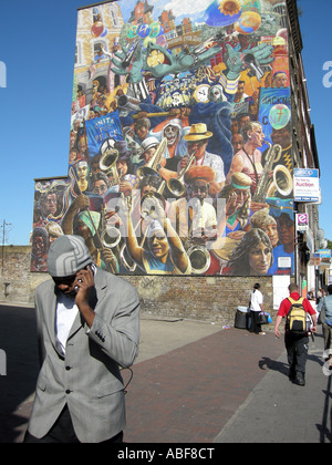 L'afro-caraïbes man walking passé une murale communautaire À HACKNEY London England Photo © Julio Etch Banque D'Images