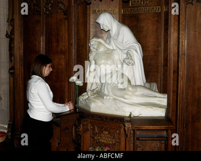 Femme en prière avec le chapelet en face de Pieta statue de Vierge Marie tenant le corps de Jésus Christ Banque D'Images