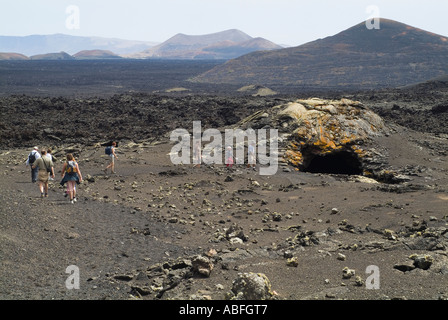 Dh Le Parc National de Timanfaya LANZAROTE TIMANFAYA Visite guidée les randonneurs de trekking à travers les bombes de lave fusiformes à bulle tunnel Banque D'Images