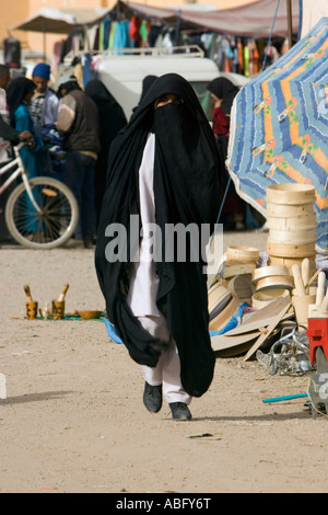 Femme en robe noire traditionnelle couvrant la tête de la rue du marché à Jorf Tafilalt Maroc Banque D'Images