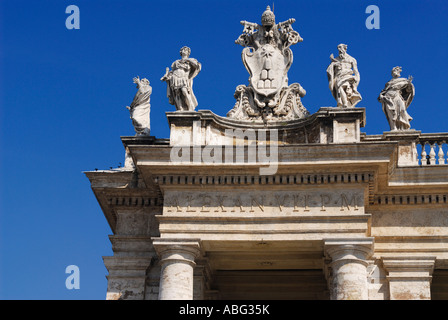 Détail de l'Armoiries du Vatican et des statues de saints et le Pape sur St Peters Square colonnades Basilique Papale Rome Italie avec ciel bleu Banque D'Images