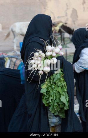 Robe noire femme avec assortiment de légumes racines street market Jorf au Tafilalt Maroc Banque D'Images