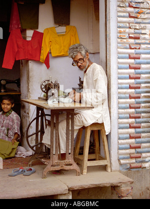 Travail sur mesure sur sa machine à coudre dans l'avant de son petit magasin dans le Nord de l'Inde Banque D'Images