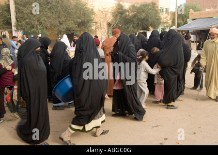 Les femmes en robes noires et couvre-chef cachant visages à la rue du marché dans la région de Jorf Tafilalt Maroc Banque D'Images