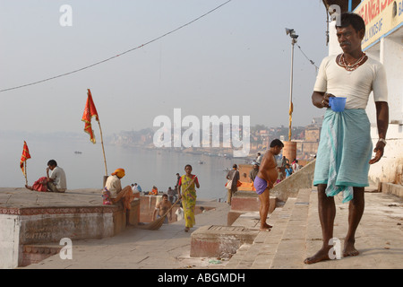 Homme debout sur les ghats avec un verre d'eau en début de matinée, Varanesi, Inde Banque D'Images