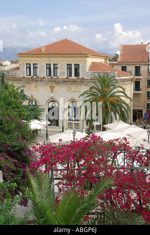 Corfu Grèce Greek island & Vieille ville bougainvilliers colorés autour d'affaires restaurant tourisme de plein air avec des tables à l'ombre sous un grand parasol couvrir Banque D'Images