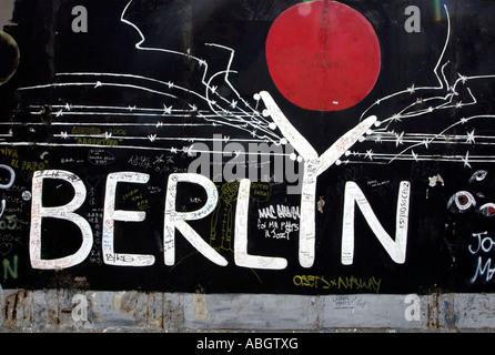 Les gens passent devant le côté est du mur de Berlin, décorée par les artistes Berlin Allemagne Banque D'Images