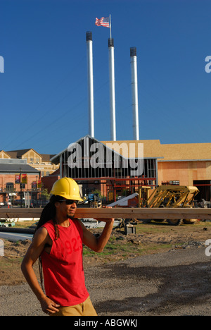 Jeune homme noir avec hard hat carrying lumber sur l'épaule sur un site de construction à Bend Oregon USA Banque D'Images