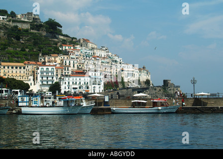 Amalfi Town front de mer petits bateaux amarrés à la jetée développement de construction bondée le long des falaises du rivage à Salerne Campanie du sud de l'Italie Europe Banque D'Images