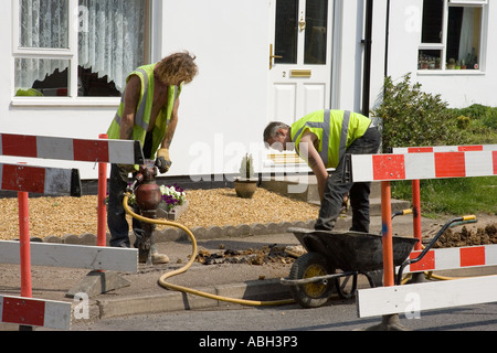 Les travailleurs de la route de creuser une tranchée pour installer les câbles d'utilité en UK Banque D'Images