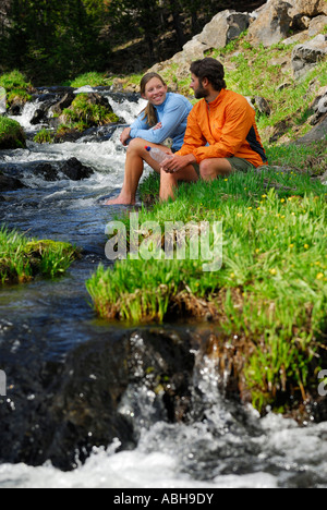 Paire de sains jeunes randonneurs reposant, avec les pieds dans un ruisseau de montagne froide Oregon USA Banque D'Images