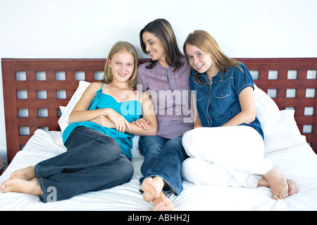 La mère et les deux adolescents assis sur un lit, à l'intérieur Banque D'Images
