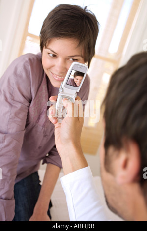 Man photographing young woman with camera phone Banque D'Images