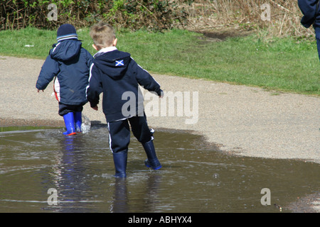 Deux garçons éclaboussant par une flaque d'eau dans leurs bottes, Ecosse, Royaume-Uni Banque D'Images