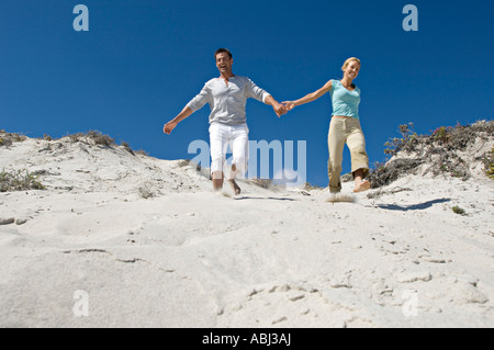 Couple Holding Hands, courant le long des dunes de sable Banque D'Images