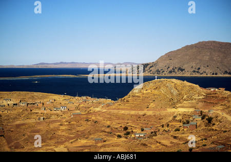 Le lac Titicaca, au Pérou. Vue sur le lac avec un petit village aride et une croix blanche au sommet d'une colline. Banque D'Images