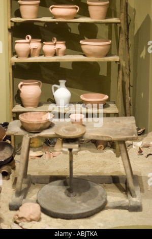 Intérieur d'un ancien atelier de céramique polonaise historique avec une roue de poterie traditionnelle et des étagères en bois rustiques avec des pots en terre cuite. Banque D'Images