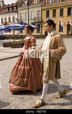 Jeune courtisan en vieux costumes traditionnels à Sandomierz, Pologne. Homme et femme en robe d'époque marchant sur la rue pavée dans la ville historique. Banque D'Images