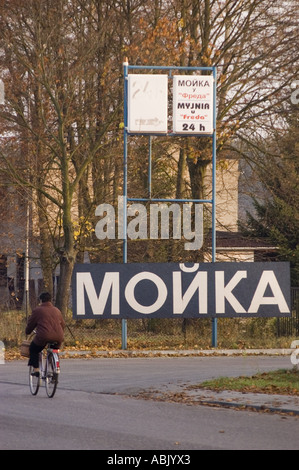Publicité en langue russe de lavage de voiture sur la route de Varsovie Berlin pour gros camion TIR, montrant un grand panneau de bord de route et un cycliste au premier plan. Banque D'Images