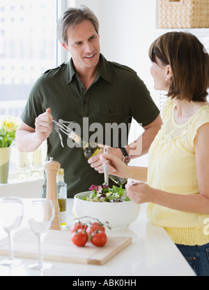 Couple tossing salad et vin d'ouverture Banque D'Images