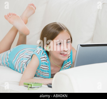 Girl using laptop on sofa Banque D'Images