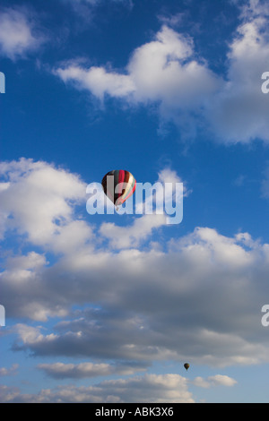 Jaune et rouge crimson hot air balloon contre un ciel bleu profond avec des nuages Banque D'Images