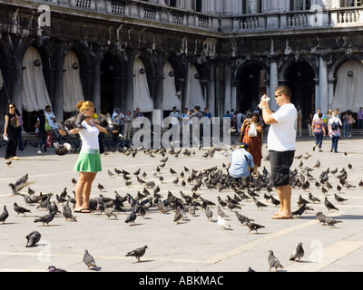 Man photographing girl nourrir les pigeons de la Place Saint Marc Venise Banque D'Images