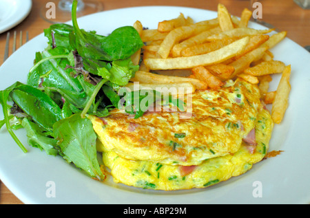 Une omelette au jambon, fromage et herbes accompagné de pommes de terre frites et une salade verte Omelette Banque D'Images