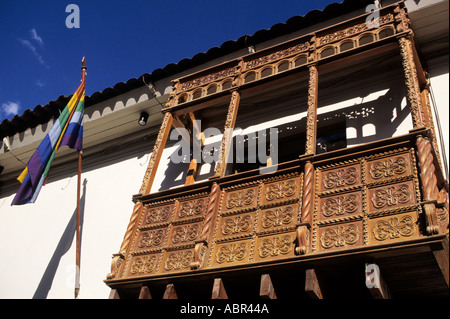 Cusco, Pérou. Balcon en bois sculpté typique avec le drapeau arc-en-ciel de Cusco. Banque D'Images