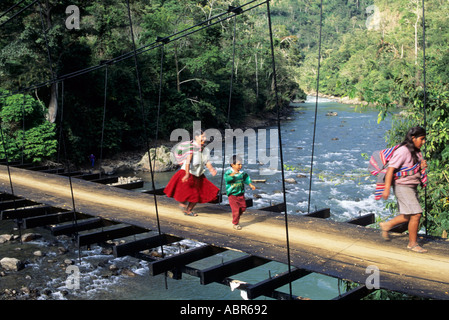 San Juan del Oro, le Pérou. Deux femmes quechua et un garçon traverser un pont suspendu pour piétons sur une rivière. Banque D'Images