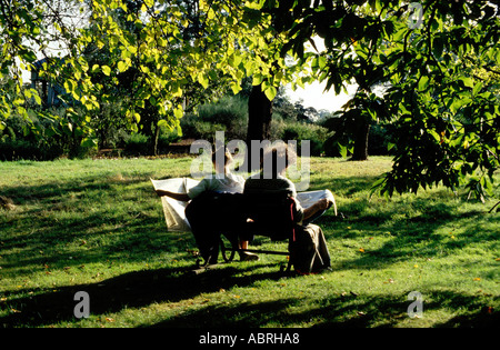 L'homme et la femme s'assit sur le banc de parc de lire les journaux Banque D'Images