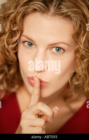 Young woman looking at camera avec le doigt à la bouche Banque D'Images