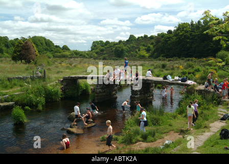 Les enfants qui jouent sur l'école et près de Old Stone Clapper Bridge à Postbridge Devon, Angleterre Royaume-Uni UK Banque D'Images