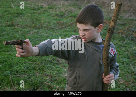 Un garçon de 6 ans utilise un bâton comme une arme pendant la lecture, UK. Banque D'Images