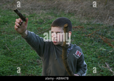 Un garçon de 6 ans utilise un bâton comme une arme pendant la lecture, UK. Banque D'Images