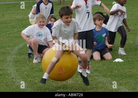 Une école primaire garçon saute sur un ballon sauteur au cours d'une journée du sport scolaire, Clissold Park, Londres, UK. Banque D'Images