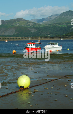 Barmouth bateaux amarrés et petits yachts dans le viaduc ferroviaire de l'estuaire de Mawddach Afon et passerelle au-delà Banque D'Images