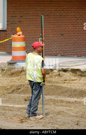 Travailleur avec appareil de mesure laser pour contrôler la profondeur adéquate lors de la construction de New Street Banque D'Images