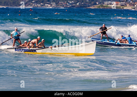 Les équipes de Surfboat ride les vagues en mer au cours de la Nouvelle Galles du sud de sauvetage sur plage plage de Cronulla au Carnaval Banque D'Images