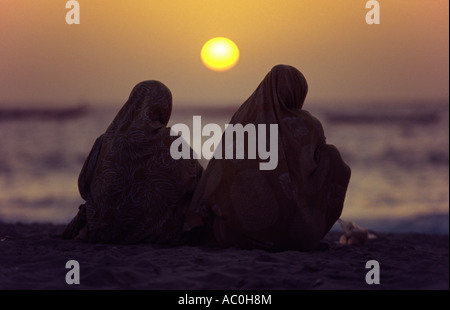 Les femmes mauritaniennes enveloppées de melafas sont silhouetté contre le soleil de l'après-midi à la plage des Pecheurs Fishermens Beach Banque D'Images