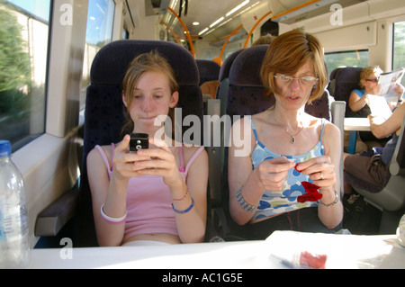 Mère et fille s'ennuie à coudre faire jouer à des jeux sur téléphone mobile sur British train Banque D'Images