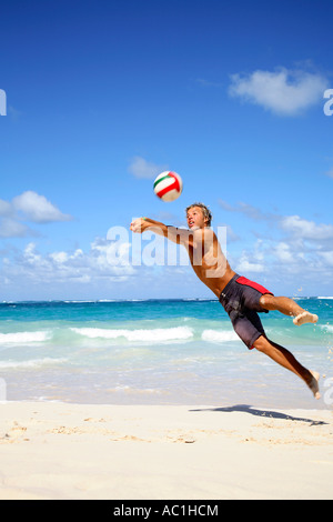 Jeune homme jouant du volley-ball sur plage Banque D'Images