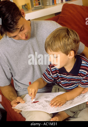 Père de regarder son jeune fils jouer avec un livre de coloriage Banque D'Images